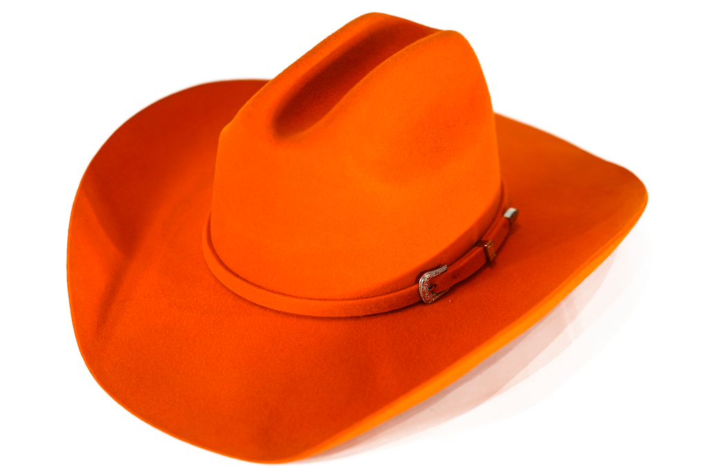 A classic cowboy hat in a warm rust-orange color, featuring a matching band with a silver buckle, set against a plain white background.